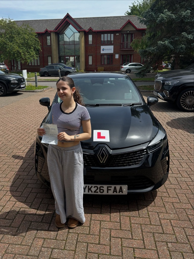 Student holding DVSA Practical Test Pass Certificate next to Clear Roads training car